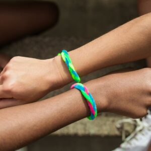 Two wrists with colorful friendship bracelets in a close-up view, symbolizing friendship.